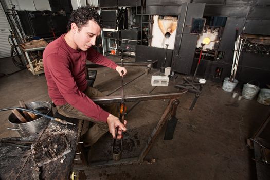 Young male glass worker with object and tools 