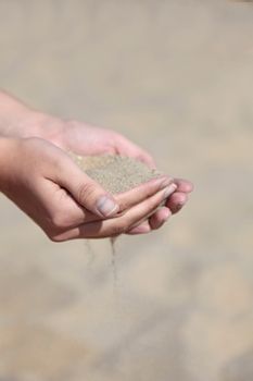 A person holding dry sand in his hands.