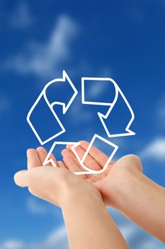 A person holding a symbol for sustainability in front of a bright blue sky.