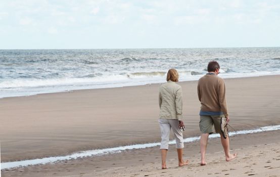 Middle aged man and woman taking a walk on the beach.