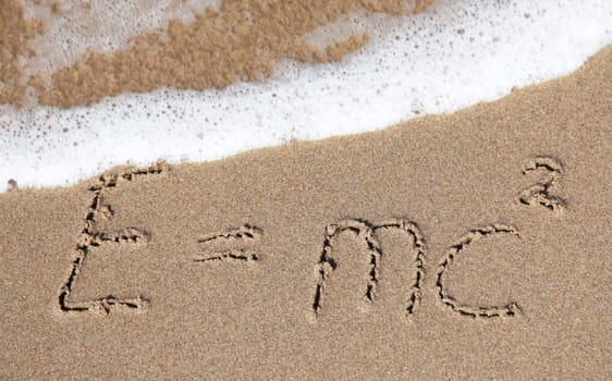 Writings in the sand on the beach symbolizing E=mc².