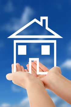 A person holding a stylized home in front of a bright blue sky.