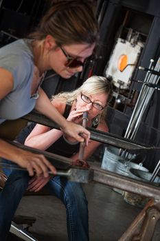 Female glass art students working together on object
