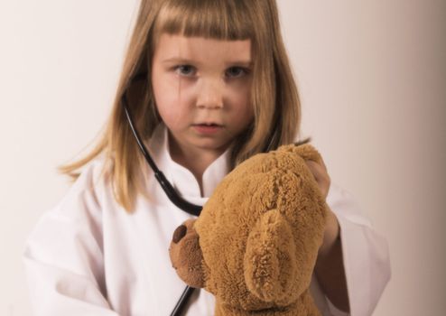 girl with stethoscope give medical examination to her's teddy bear