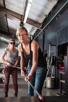 Blond glass artist working with molten glass object