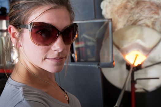 Cheerful female glass artisan near hot furnace