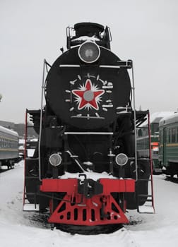 old Soviet locomotive at a train station in winter,  front view