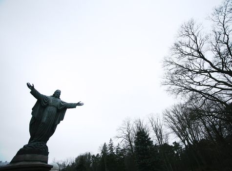 Jesus or God on a background of the sky and trees in park Palanga