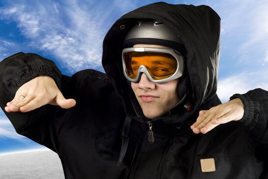 Teenager boy with orange goggles and black suit with hood and helmet acting like he's snowboarding.

Studio shot.