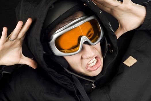 Boy dressed in snowboarding suit and helmet and googles reacting surprised on something he sees.

Studio shot.