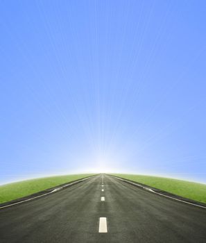 Shot of a tarmac road leading into the horizon and the sun with a blue gradient sky.