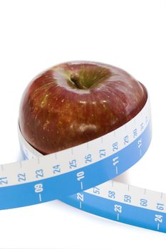 Healthy eating - Red apple with tape measure against a white background.