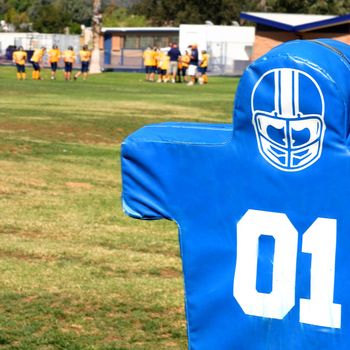 Blue tackling dummy for football practice on green grass.