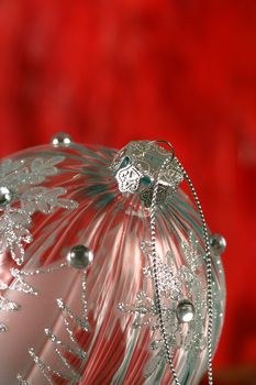 A single glass Christmas ball sitting on a red background.  Shallow depth of field - focus on hanger.
