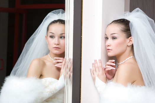 a beautiful bride seriously looks in the mirror