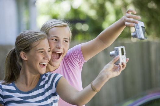 Teen girls taking each other�s picture with digital cameras