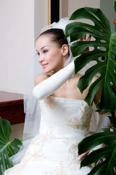 a happy bride near the big green leaf of the flower 