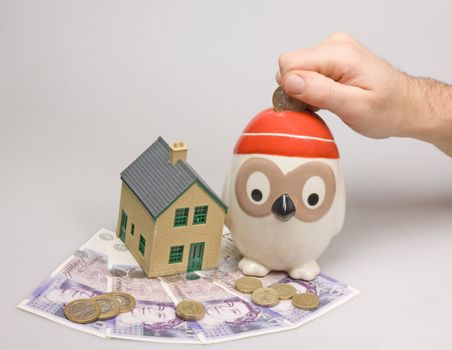 money box with house and british pounds saving and investment concept