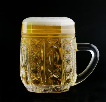 Glass cup  of beer on a black background with the foam 