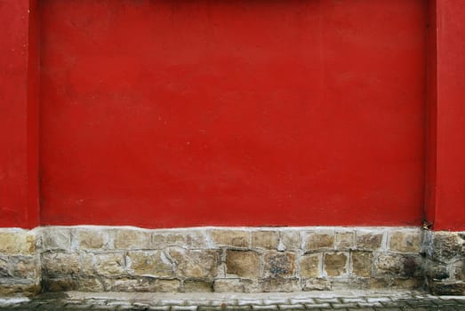 Red plastered house wall and stone base