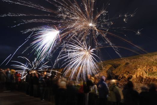 Crowd watching large fireworks display. Slow shutter speed, light trails.