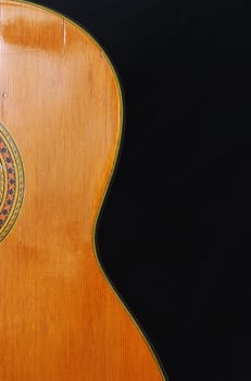 Detail of classic guitar (Spanish), against black background.