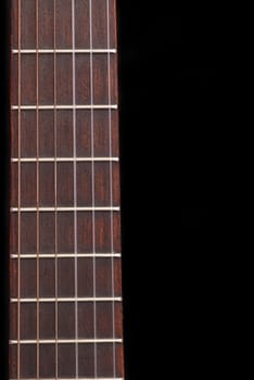 Detail of classic guitar (Spanish) fretboard, against black background.