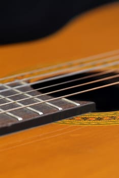 Detail of classic guitar (Spanish), against black background.