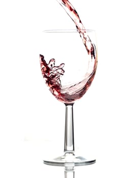 Red wine pouring into wine glass. White background, reflexion.