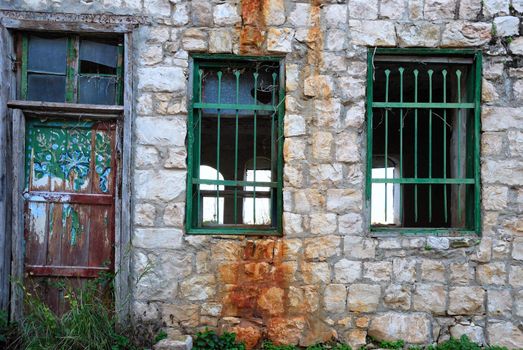 Door and windows in a facade of old abandoned house.