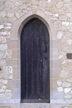 Black medieval church door surrounded by stone work.