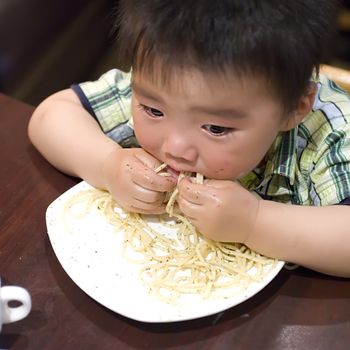 eating baby to grab pasta with hand