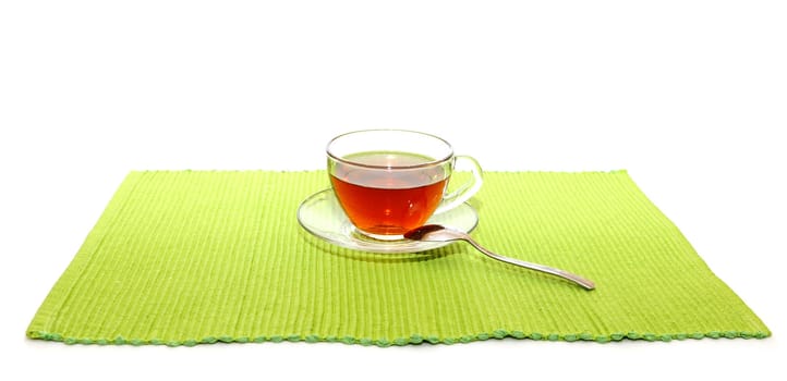 the cup of tea with spoon on the green napkin