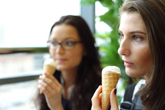 women on foreground licking ice cream 