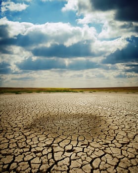 last wet spot in cracked earth under dramatic sky