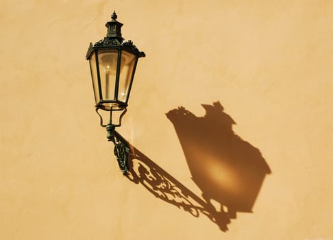 Wrought-iron lantern with its shadow on the yellow wall, Prague, Czech Republic