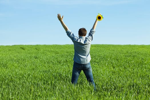 young man standing with a sunflower in the green field