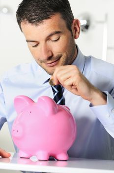 businessman matting a coin in the piggy-shaped pink pig