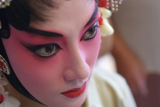 a chinese opera actress is painting her face backstage