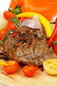 Roasted Beef with Grilled Vegetables, Spices, Peppercorns, Onion, Garlic and Herbs closeup on Wooden Board 