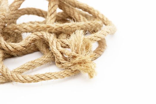 Coiled household rope with a frayed unravelled end and fibre texture on a white background