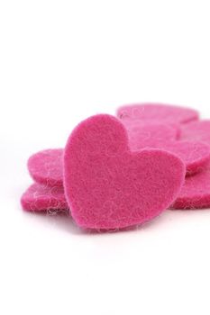 Romantic pink textile hearts with fibre texture in a pile with a single heart facing the camera for a Valentine or anniversary greeting
