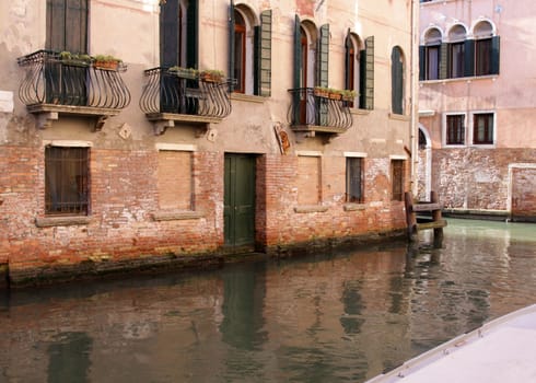 A canal in Venice, Italy, lined with a building with overlooking balconies.