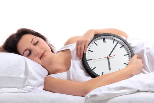 A young woman sleeping with a clock in her arms. All on white background.