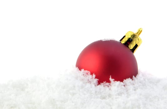 A red glitter ball lying in the snow.