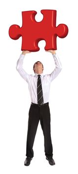 A young businessman stemming a huge piece of a puzzle. All on white background.