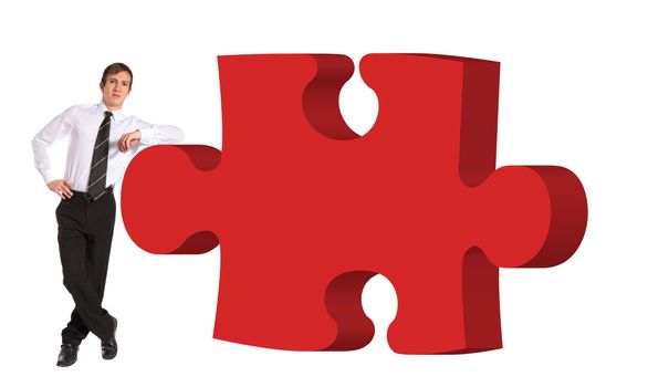 A young businessman standing next to a piece of a puzzle. All isolated on white background.