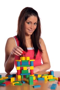 An attractive young woman plays with building bricks. All isolated on white background.