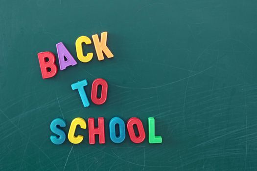 Several multicolored character forming the term back to school on a chalkboard.