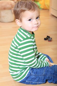 Cute european toddler playing with toy train in kindergarten.